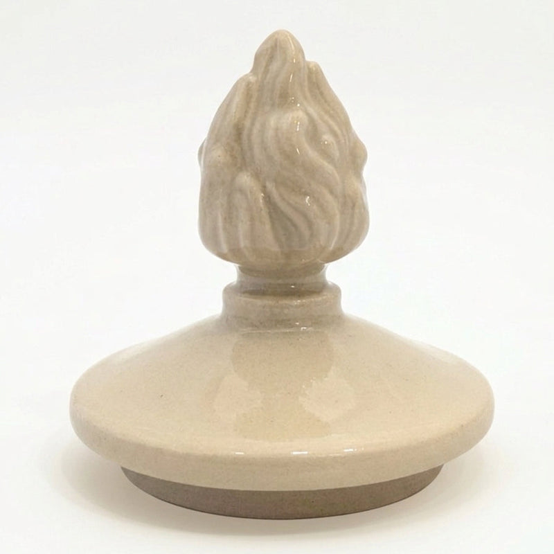 Close-up of hand-sculpted flame finial on ceramic urn lid, classical memorial symbol