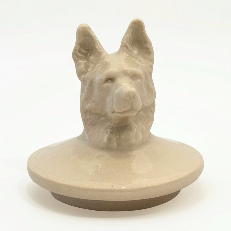 Close-up of hand-sculpted Shepherd dog figure on ceramic urn lid