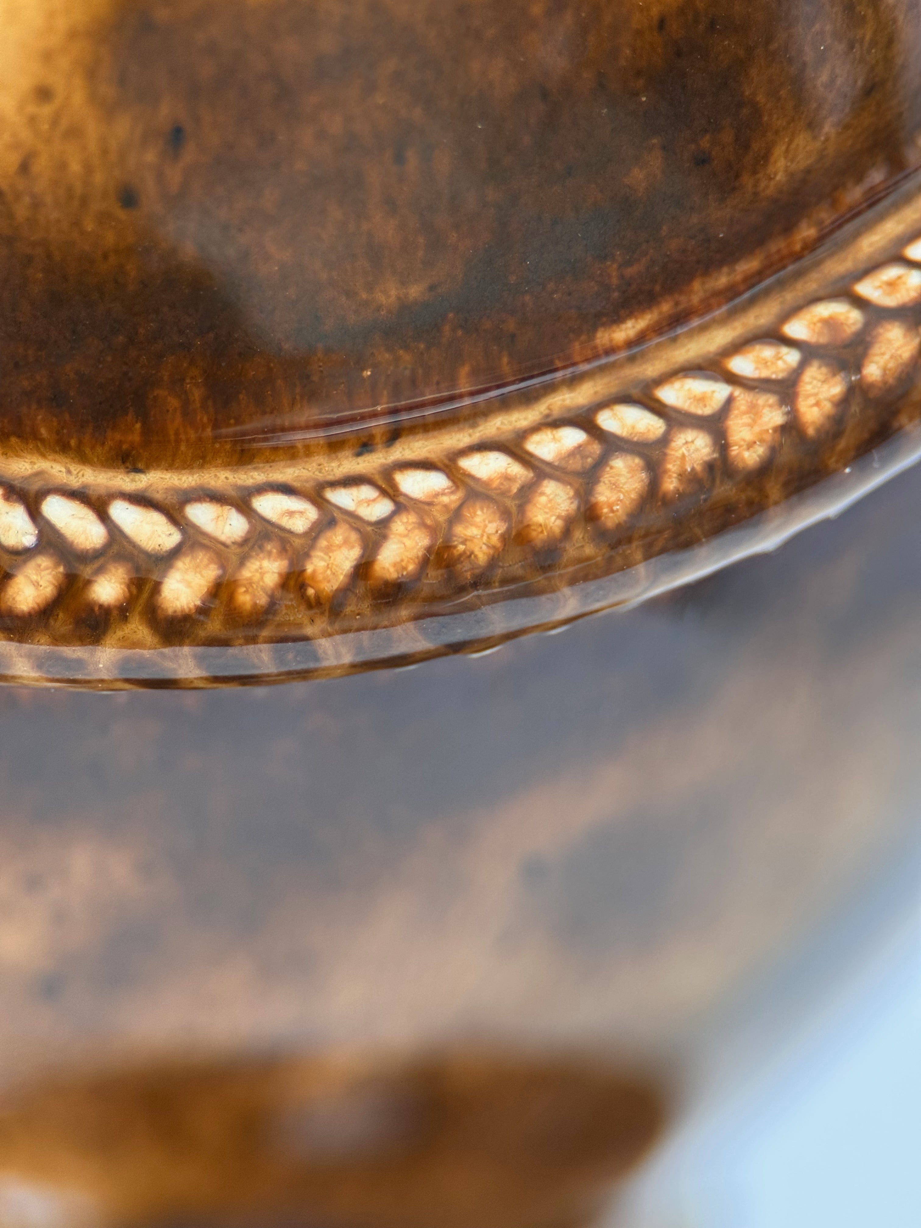 Close-up of draped rope relief detail on ceramic pet memorial urn, tawny brown glaze